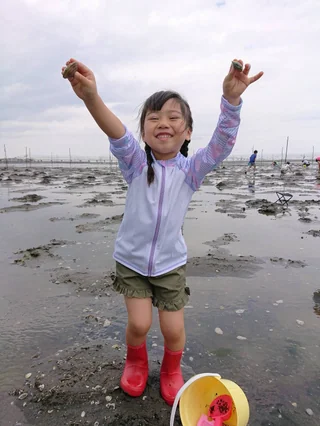 干潟で両手を上げて喜ぶ子ども