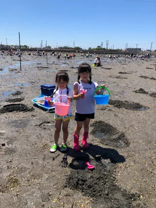 バケツを持って干潟に並ぶ子ども2人