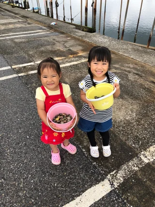 貝を入れた容器を見せる子ども2人