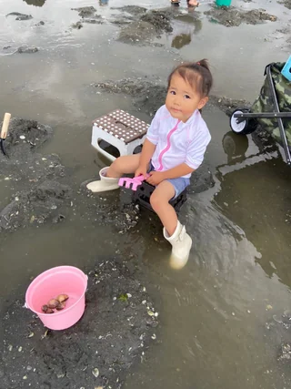 バケツのそばで干潟にしゃがむ子ども