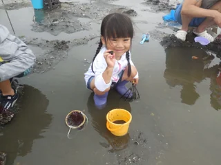 黄色いバケツのそばにしゃがむ子ども