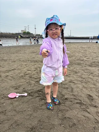 青い柄の帽子をかぶって干潟に立つ子ども