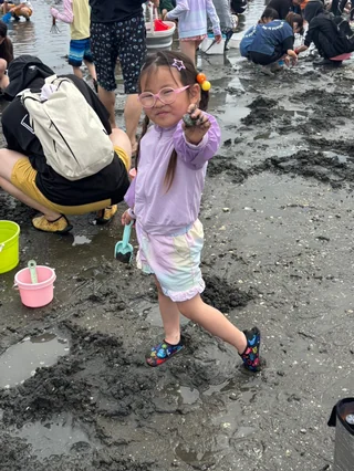 干潟で手を顔の近くに上げる子ども