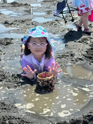 泥の中の貝を両手で見せる子ども