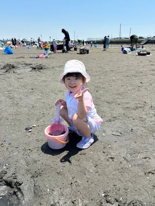 ピンクのバケツを持ってしゃがむ子ども